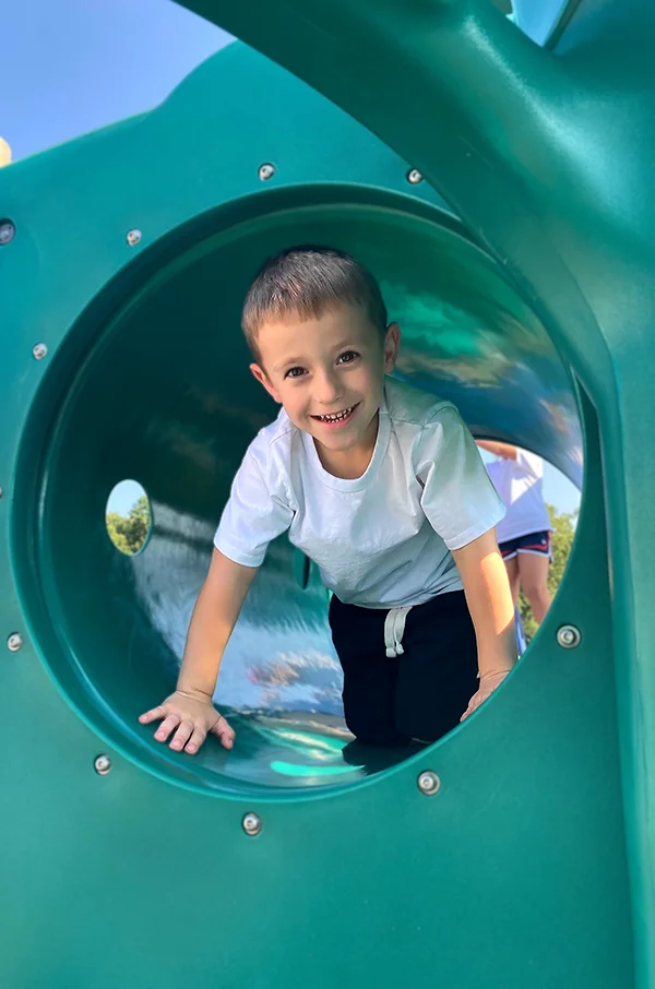 Enrollment Information for The Merit School - image of boy having fun on playground equipment