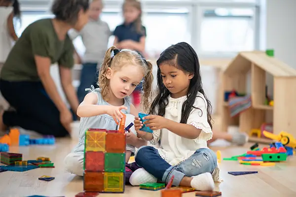 Montessori girls building together with shape blocks - The Merit School
