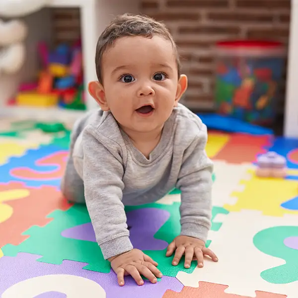 Infant Care Baby Steps childcare and newborn daycare - baby crawling on colorful, soft mat