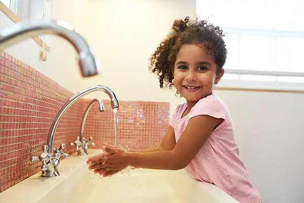 The Merit Schools Healthy Practices - smiling girl washing her hands