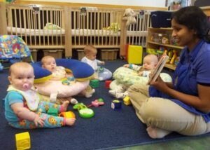 Merit School of Braemar infant circle - smiling teacher showing picture book to babies