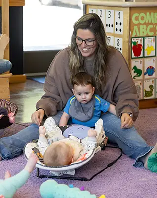 Teacher with infants at The Merit School of Doc Stone